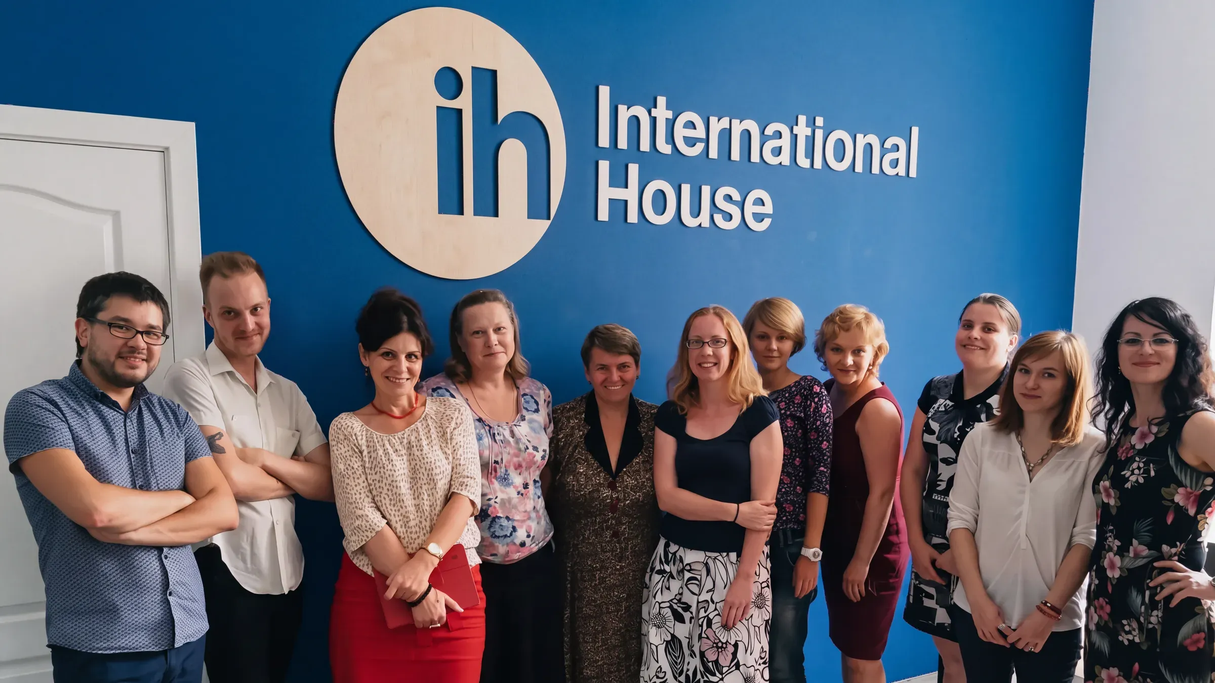 International House Kyiv team next to the school logo